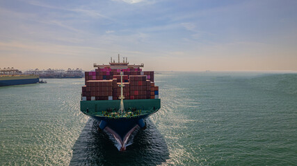 A container ship, fully loaded with goods, sails out to sea, delivering products to various locations around the world.