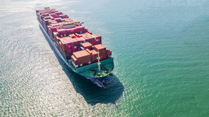 A container ship, fully loaded with goods, sails out to sea, delivering products to various locations around the world.