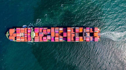 A container ship, fully loaded with goods, sails out to sea, delivering products to various locations around the world.