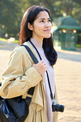 Naklejka premium woman camera backpack outdoors park sunlight travel fashion casual relaxed exploring sunny park with camera ready moments in nature during outdoor stroll and serene mood in daylight