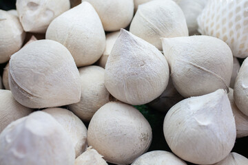 Close-up of pile of peeled young coconuts with smooth white husks for sale in supermarket in Sanya...