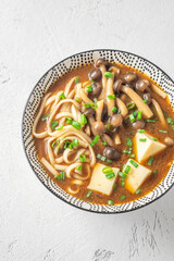 Japanese udon soup with Shimeji mushrooms, tofu, and rich dark umami broth