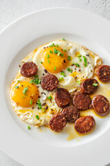 Hearty fried eggs served with caramelized chorizo slices and fresh scallion garnish