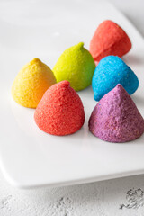 Colorful sugar-coated marshmallow pyramid candies sparkling on clean white rectangular platter