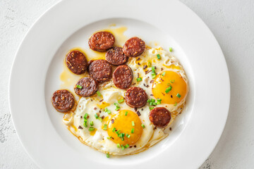 Hearty fried eggs served with caramelized chorizo slices and fresh scallion garnish