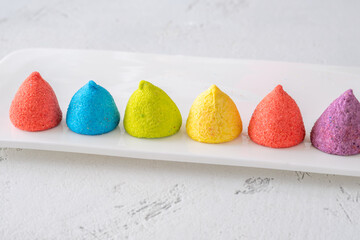 Colorful sugar-coated marshmallow pyramid candies sparkling on clean white rectangular platter