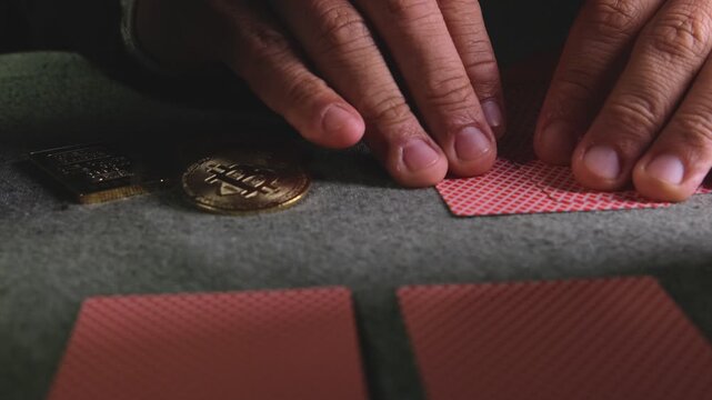 Hand holding playing cards with golden bitcoins on table