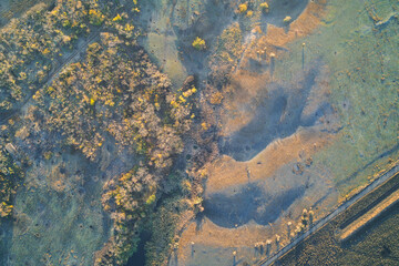 Aerial view of a scenic river landscape at sunset contrasting with destroyed buildings on the left bank, highlighting the war in Ukraine.