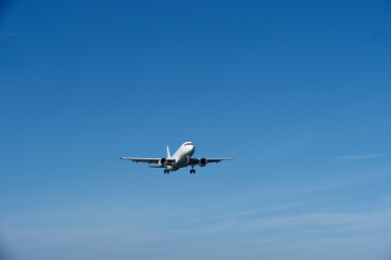 White Airplane Approaching for Landing Against Blue Sky and Clouds
