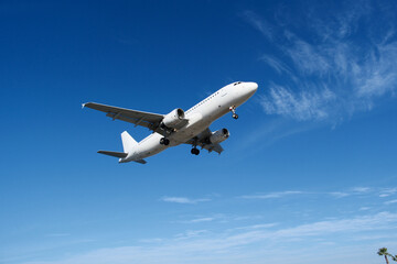 White Airplane Approaching for Landing Against Blue Sky and Clouds
