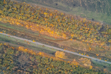 Aerial top down view of railway tracks in autumn forest with scorched earth spots. Strategic military logistics route and transport infrastructure.