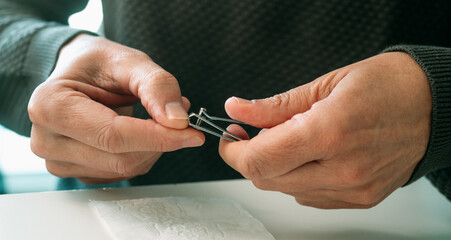 a man trims his thumb nail with precision