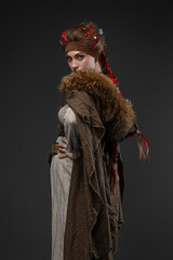 Obraz premium Young Viking warrior woman in Nordic costume with battle axe, fur cape on gray
