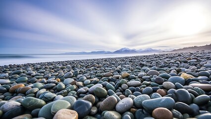 Serene beach landscape with smooth colorful pebbles and distant mountains under a cloudy sky
