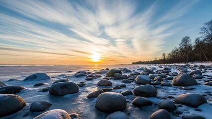 Serene winter landscape with snow covered rocks at sunset by the sea with vibrant sky