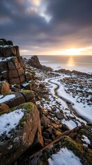 Snowy rocky coastline at sunset with cloudy sky and ocean view