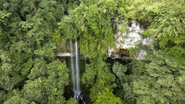 Aerial view of a cascade plunges down a rock face into a pool surrounded by dense, vibrant green foliage, El Valle de Antón, Coclé Province, Panama. - Powered by Adobe