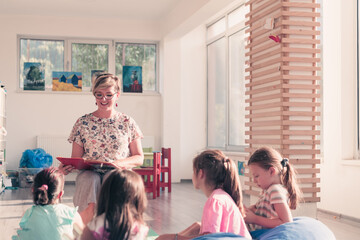 Reading time in elementary school or kindergarten, teacher reading a book to kids in elementary school or kindergaden. Selective focus