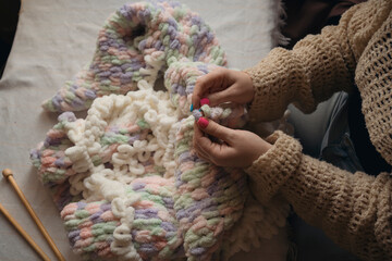 Hands making blanket from yarn without crochet hook or knitting needles