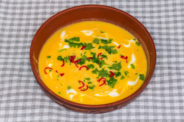 Pumpkin-lentil soup-puree with chili and greens in bowl