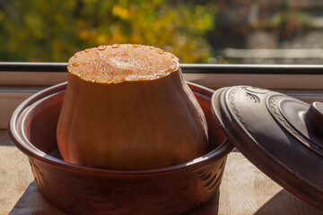 Cut butternut squash with juice drops in pot against window