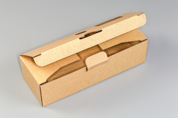 Partly open rectangular cardboard packing box on a gray background