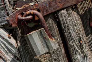 Old rusty metal padlock on a wooden door.