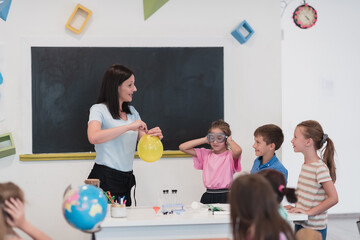 Elementary School Science Classroom: Enthusiastic Teacher Explains Chemistry to Diverse Group of Children, Little Boy Mixes Chemicals in Beakers. Children Learn with Interest