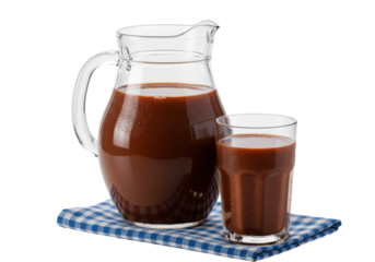 sparkling glass pitcher and tumbler of rich dark chocolate milk, showing cold condensation, on a blue checkered cloth against a high-key white studio background. concept for beverage advertising