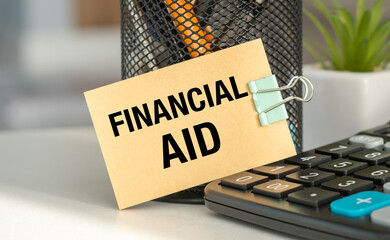 Financial Aid sign is clipped to a pen holder. A calculator is on the table next to the sign