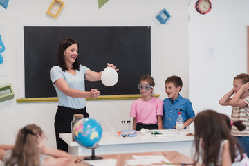 Elementary School Science Classroom: Enthusiastic Teacher Explains Chemistry to Diverse Group of Children, Little Boy Mixes Chemicals in Beakers. Children Learn with Interest