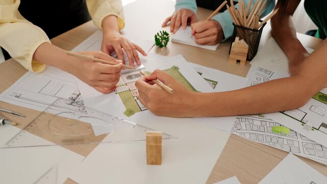 Smart architect and safety engineer discussion about building blueprint on table with architectural document, measurement tools and wooden block scatter around at modern office. Closeup. Delineation.