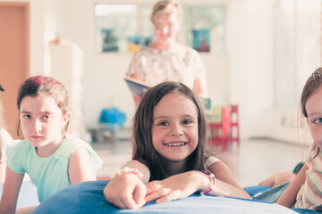 Reading time in elementary school or kindergarten, teacher reading a book to kids in elementary school or kindergaden. Selective focus