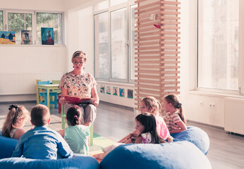 Reading time in elementary school or kindergarten, teacher reading a book to kids in elementary school or kindergaden. Selective focus