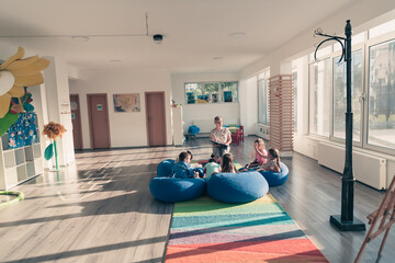 Reading time in elementary school or kindergarten, teacher reading a book to kids in elementary school or kindergaden. Selective focus