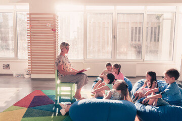 Reading time in elementary school or kindergarten, teacher reading a book to kids in elementary school or kindergaden. Selective focus