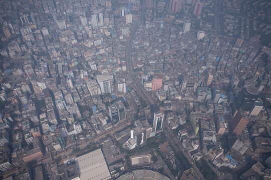 Aerial view of a sprawling cityscape, where buildings cluster tightly, streets cut precise lines, and a haze softens the urban landscape, Dhaka, Dhaka Division, Bangladesh.