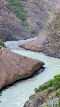 4K Vertical shot of river Chenab flowing in between the Himalayan mountain peaks as seen near Killar town in Pangi Valley, Chamba district, Himachal Pradesh, India. Scenic view of flowing Chenab river
