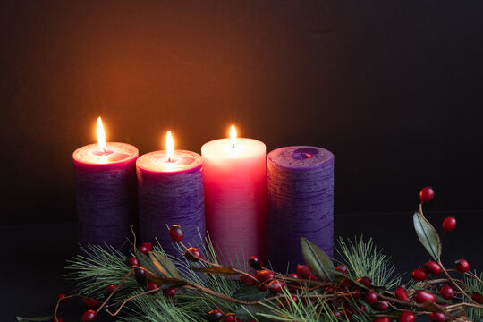 Three advent candles burning in the darkness with evergreen border