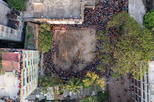 Aerial view of a vibrant gathering of people, their colorful clothing a stark contrast to the surrounding buildings and trees, Dhaka, Dhaka Division, Bangladesh.