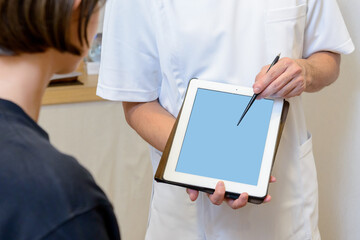 タブレットを手に持ち内容を指し示す医療スタッフ