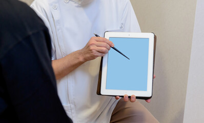 タブレット画面を使って説明する医療スタッフの手元