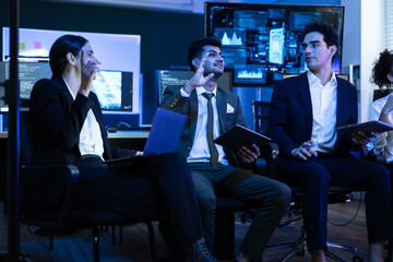 Diverse group of smiling data analysts and IT professionals collaborating in a meeting. Colleague raises his hand enthusiastically to share an innovative solution during a successful strategy session