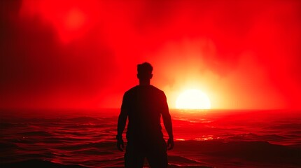 Stunning silhouette of a determined man facing the vibrant, fiery red ocean sunset symbolizing challenge and triumph