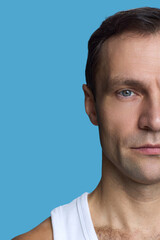 Obraz premium Portrait of Caucasian middle aged man looking at camera with serious expression, closeup of face and upper torso against blue background, short brown hair visible