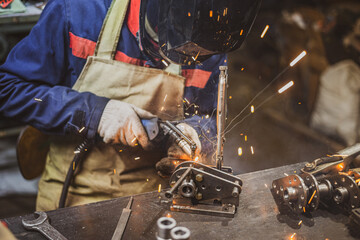 Atmospheric photo workshop with an employee welding small parts to the mechanism. industrial...