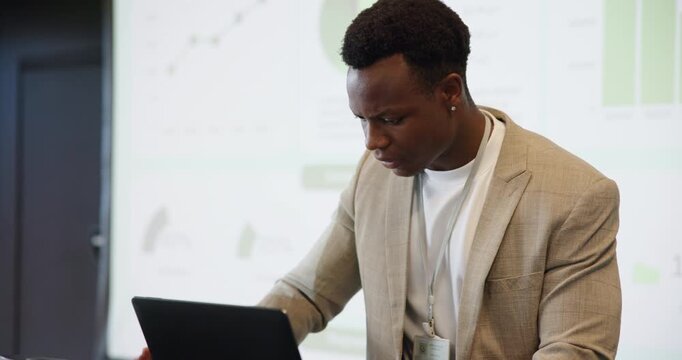 Data, laptop and sweating with black man speaker on stage in auditorium for seminar or workshop. Computer, projection screen and tissue with nervous employee at podium for presentation of statistics