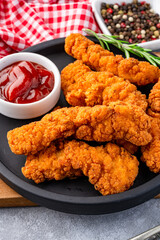 Fried chicken breast strips on grey table background. Delicious chicken crisps