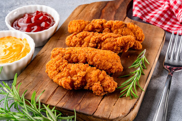 Fried chicken breast strips on grey table background. Delicious chicken crisps