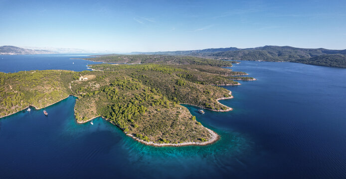 Aerial view of the sun-kissed Croatian coastline, where turquoise waters meet the verdant, rugged terrain of Stari Grad, Split-Dalmatia County, Croatia.